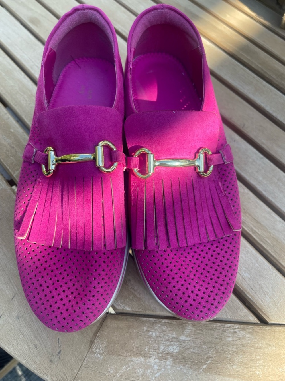 Fuscia slip on loafers with gold hardware on top.